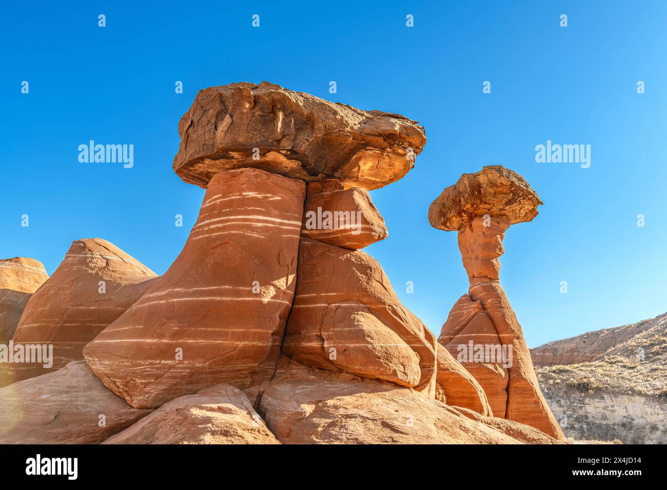 Lo hoodoo in pietra arenaria bianca e rossa a Kanab Utah mostra guglie altamente erose e rocce più dure bilanciate sulla parte superiore incorniciate da un cielo blu. Foto Stock