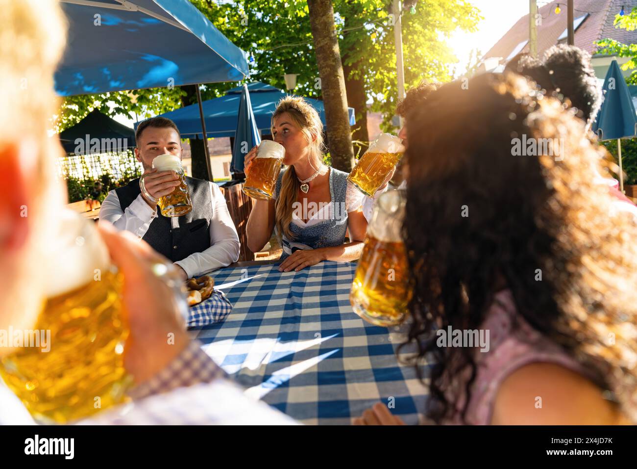 Due coppie felici seduti nel giardino della birra bavarese e godere la birra e il sole Foto Stock
