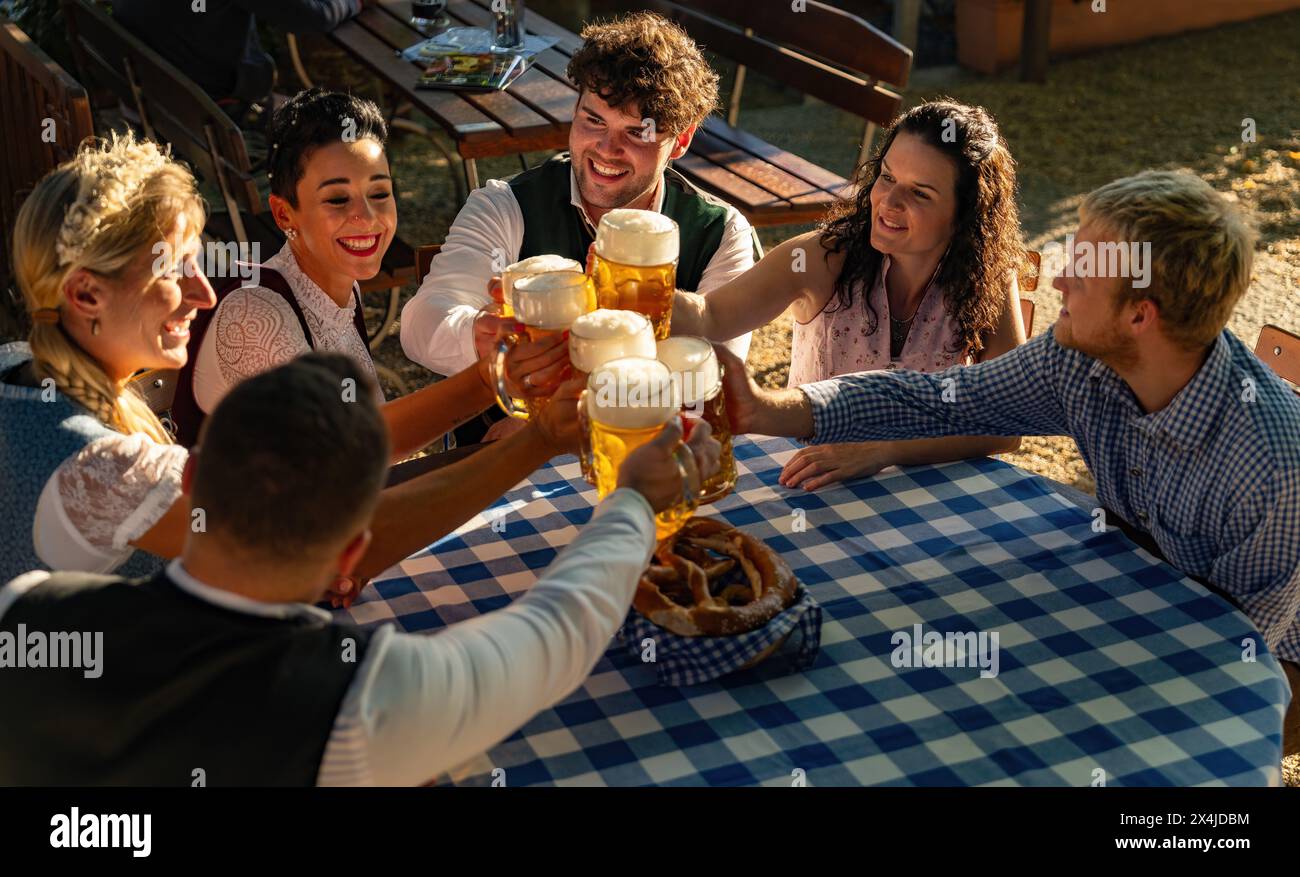 La gente si diverse a mangiare e bere nella birreria bavarese in una giornata di sole Foto Stock