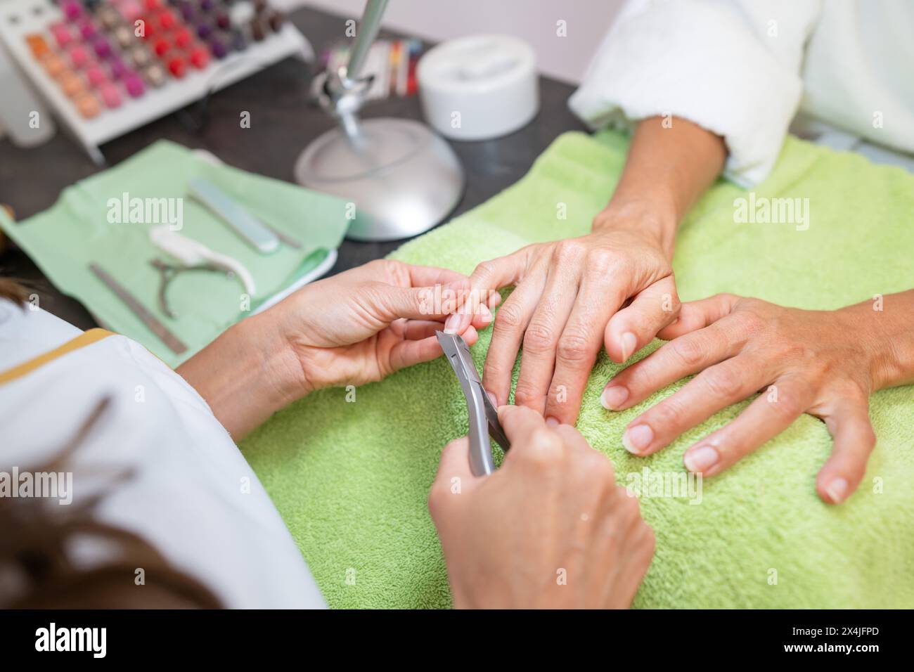 Manicurista che taglia le cuticole di un cliente in un salone con attrezzi sul tavolo in un salone di bellezza Foto Stock
