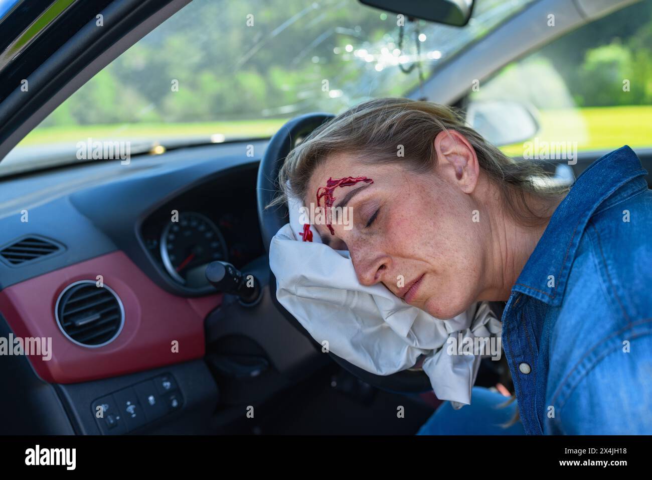 Donna incosciente con lesioni alla testa appoggiata all'airbag all'interno dell'auto dopo l'incidente. Foto Stock