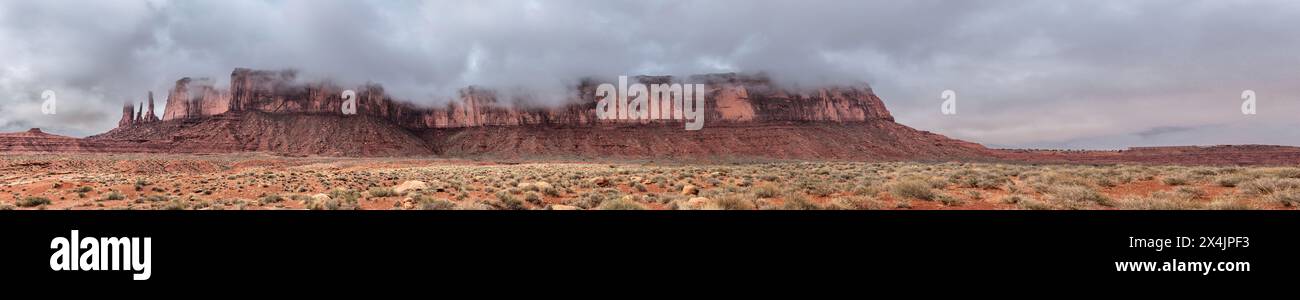 Un panorama della catena montuosa che ospita le famose guglie delle tre Sorelle nella Monument Valley, Arizona, sulla sinistra dell'immagine durante una giornata di pioggia. Foto Stock