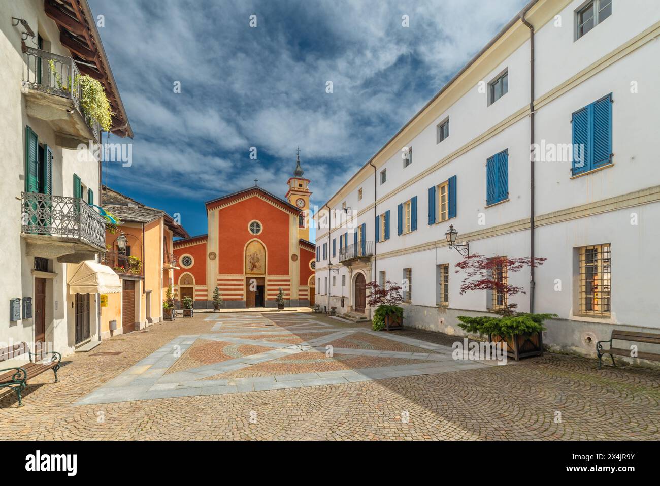 Sanfront, Cuneo, Italia - 3 maggio 2024: Piazza Ferrero lastricata di porfido e lastre di pietra con la chiesa parrocchiale di San Martino Foto Stock