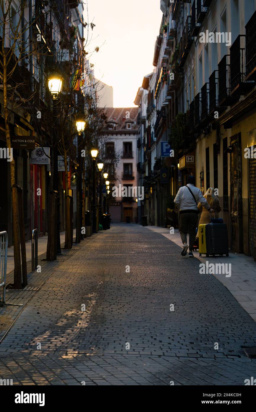 Madrid, Spagna. 11 febbraio 2024 - due persone che rotolano valigie per le strade di Madrid, in Spagna, la sera. Foto Stock