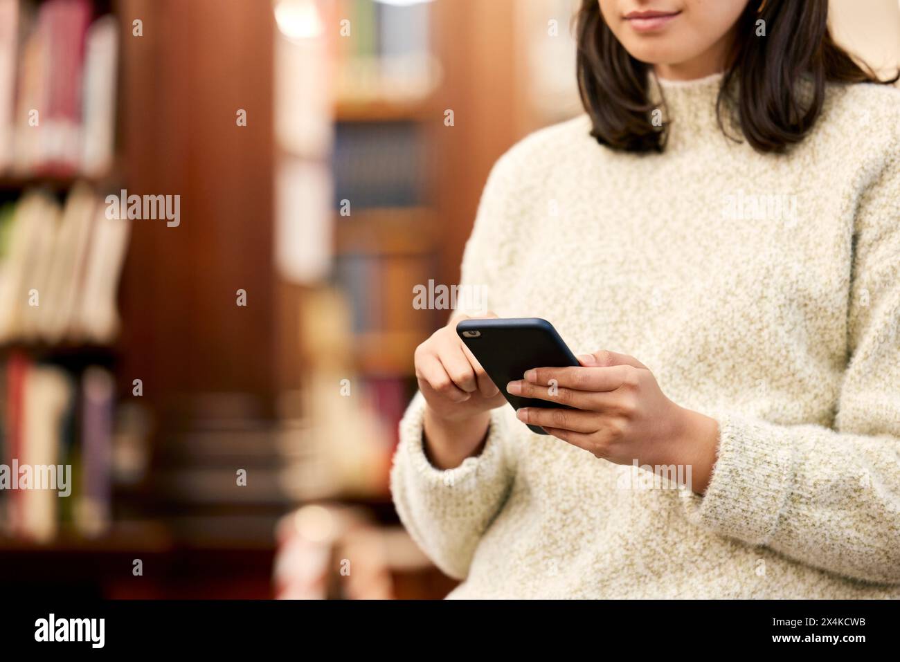 Università, biblioteca e mano di ragazza con telefono per ricerca letteraria, sito web del campus o social media. Studente, borsa di studio e persona con Foto Stock