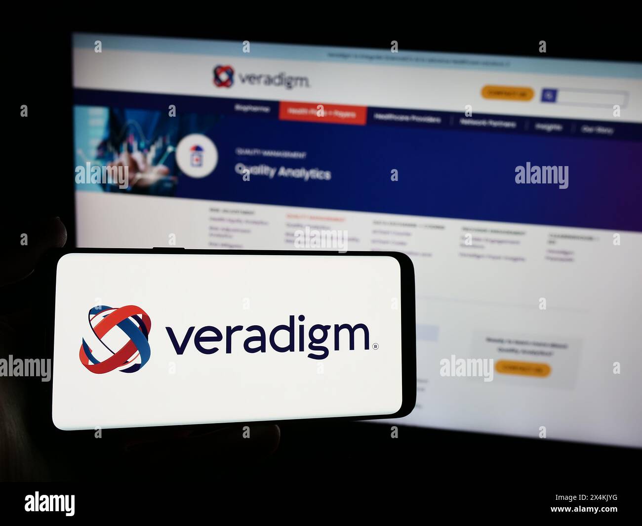Persona con smartphone con logo della società statunitense di software sanitari Veradigm Inc. Davanti al sito web. Mettere a fuoco il display del telefono. Foto Stock