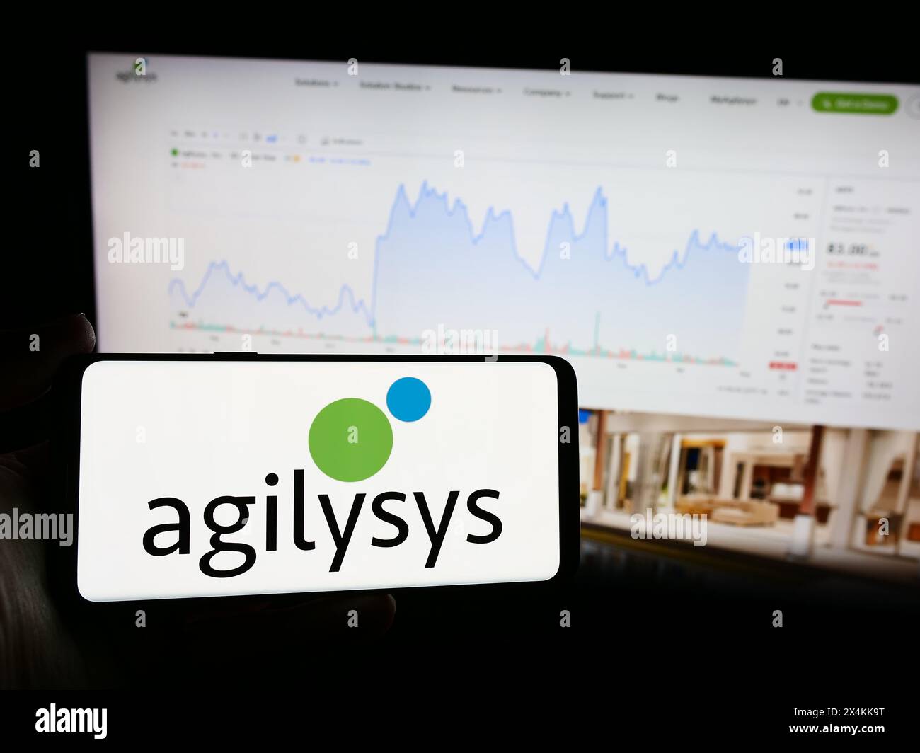 Persona che detiene un telefono cellulare con il logo della società americana di software aziendale Agilysys Inc. Di fronte alla pagina Web aziendale. Mettere a fuoco il display del telefono. Foto Stock