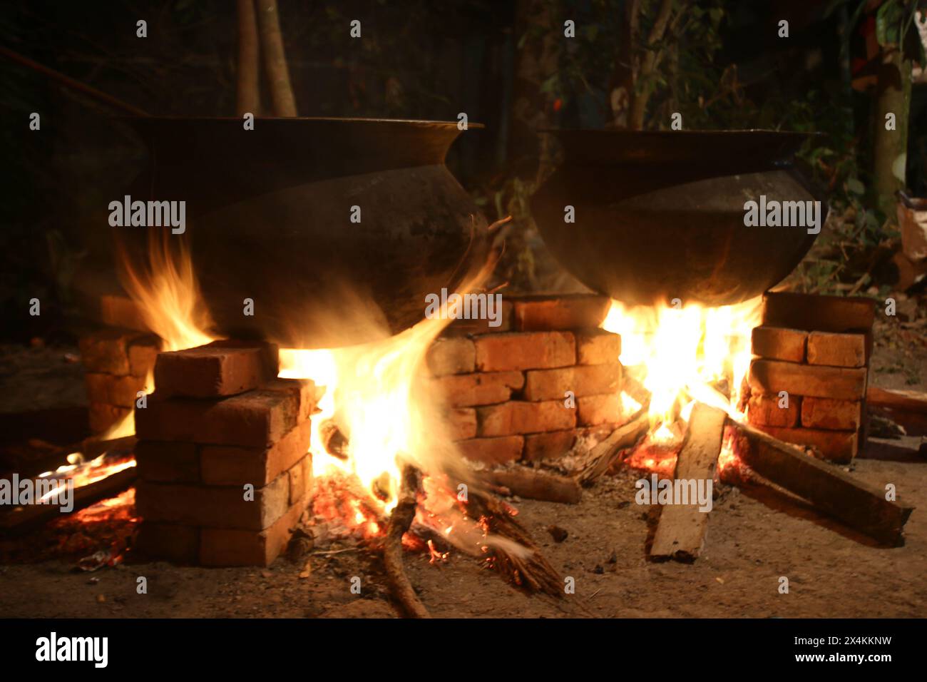 Biryani cucina in una festa del villaggio su un forno temporaneo in mattoni. Cucina all'aperto per molte persone in una grande teglia di alluminio nel fuoco a legna. cucina enorme Foto Stock