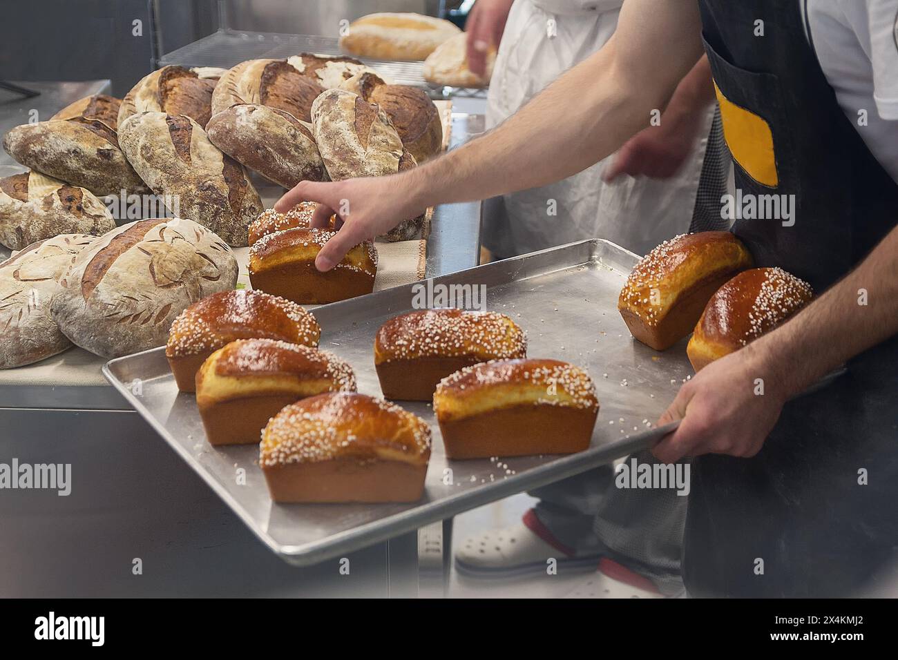 Il panettiere in una panetteria mette il pane fresco su un vassoio Cibo Foto Stock