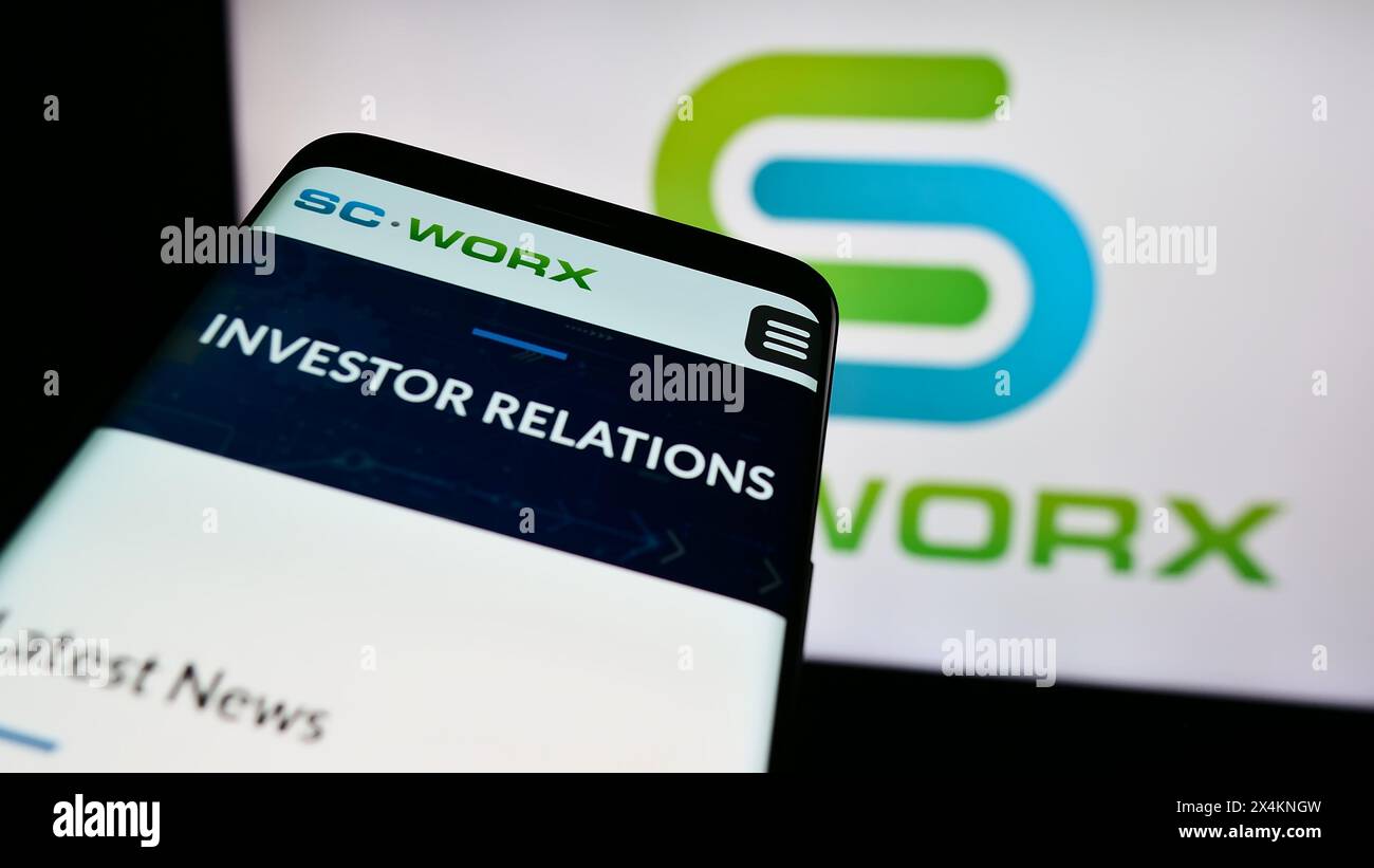 Telefono cellulare con sito web della società statunitense SCWorx Corp. Di fronte al logo aziendale. Mettere a fuoco in alto a sinistra sul display del telefono. Foto Stock
