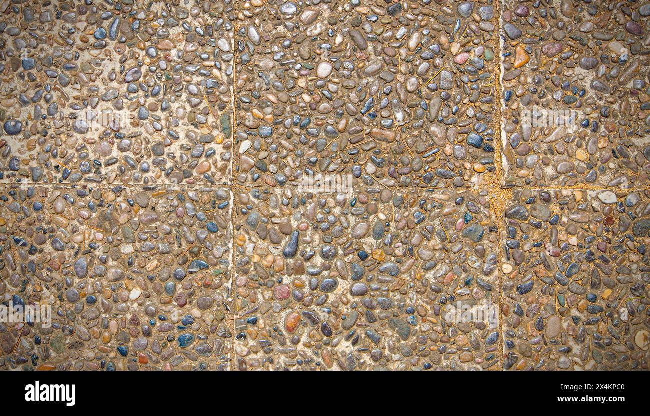 Superficie ruvida della finitura di aggregato esposta, pavimento lavato in pietra, realizzato in piccola pietra arenaria di colore marrone chiaro Foto Stock