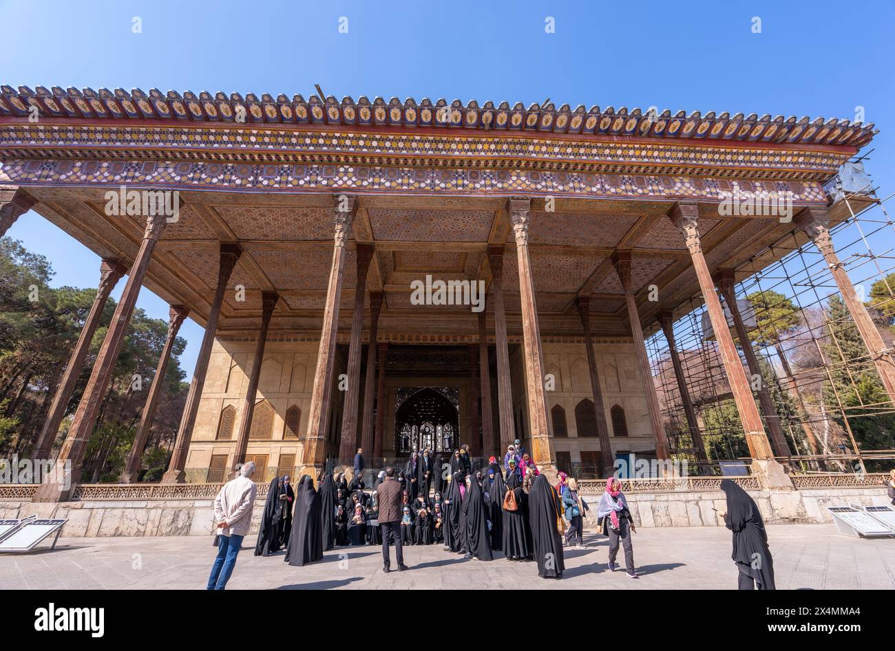 Palazzo Chehel Sotun, Iran - 5 marzo 2024: Un gruppo di turisti si riunisce all'ingresso maestoso dello storico palazzo persiano con il suo squisito bosco Foto Stock