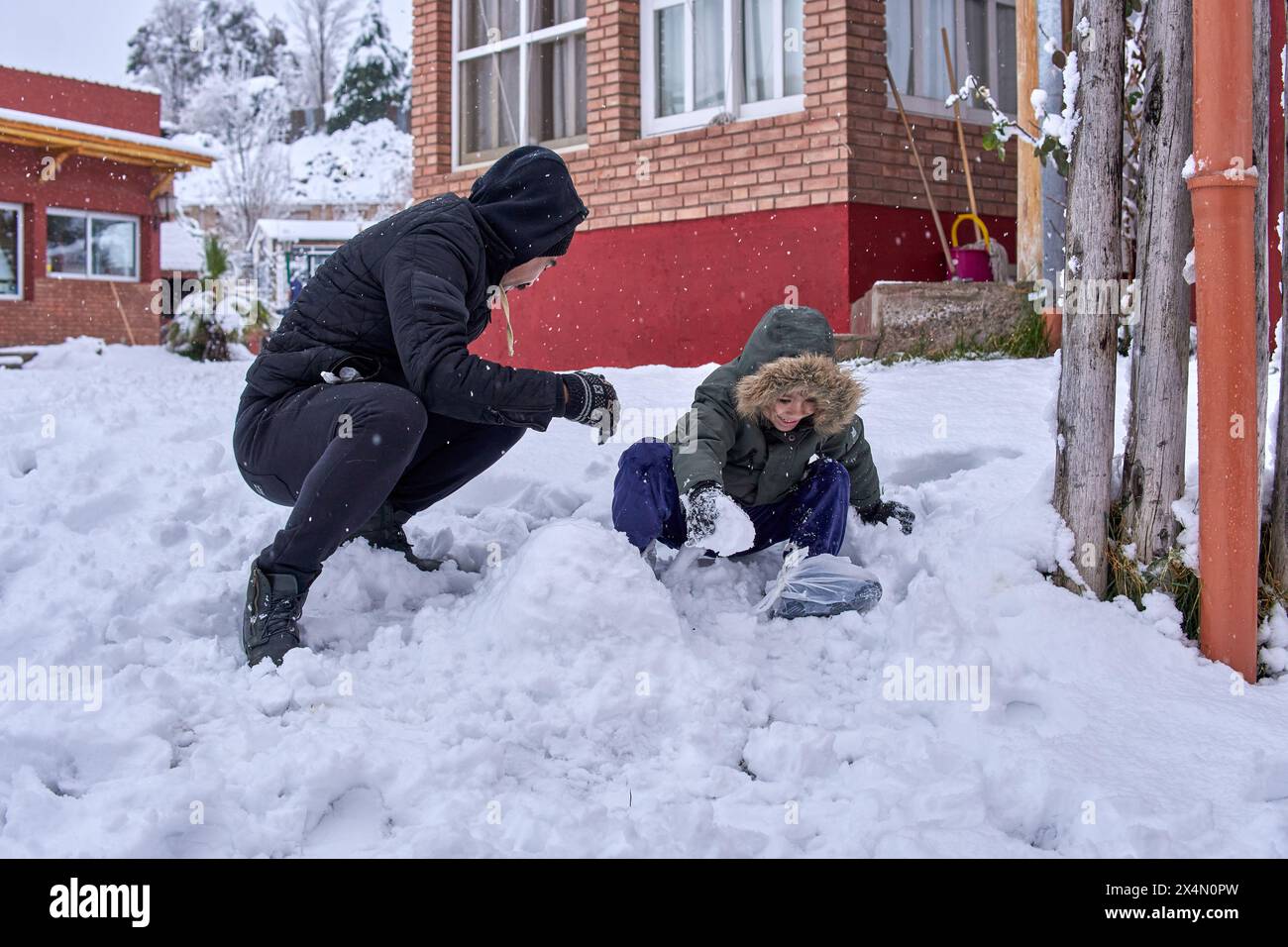 Padre e figlio latino che giocano nella neve. Vacanza in un resort di cabine a Mendoza, Argentina. Foto Stock