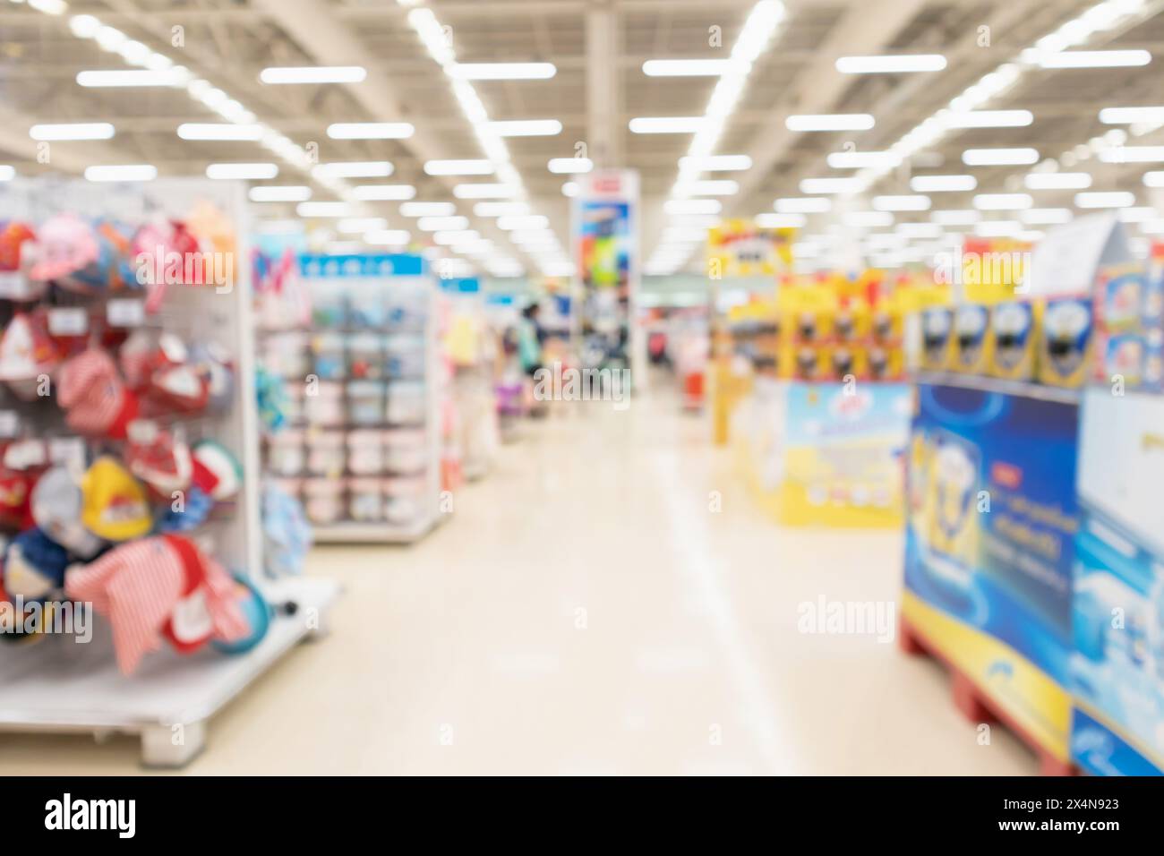 sfocatura astratta del corridoio del supermercato sfondo interno con latte artificiale per neonati e abbigliamento sugli scaffali Foto Stock