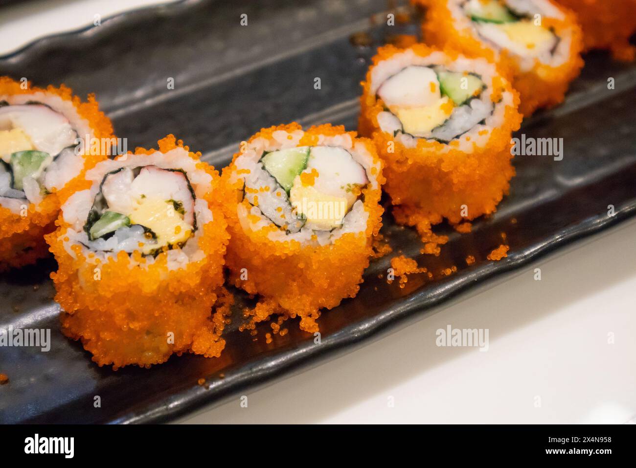 Sushi roll californiano maki su piatto nero, cibo giapponese Foto Stock
