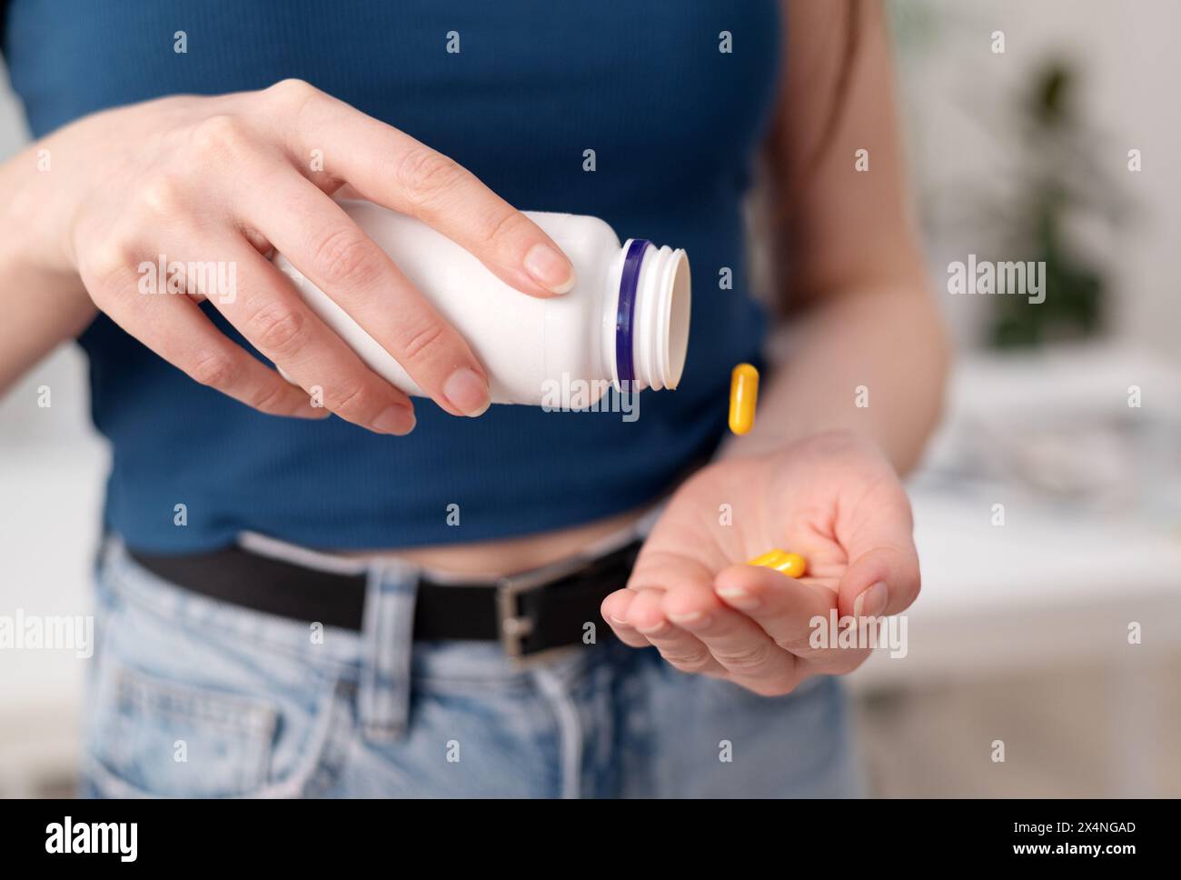 Una giovane donna tiene in mano pillole gialle, una femmina prende integratori e vitamine da una bottiglia, primo piano Foto Stock