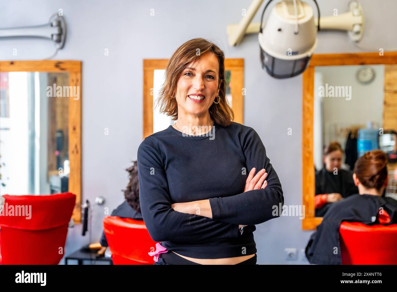 Ritratto di una donna orgogliosa proprietaria di un parrucchiere in piedi con le braccia incrociate che sorridono alla fotocamera Foto Stock