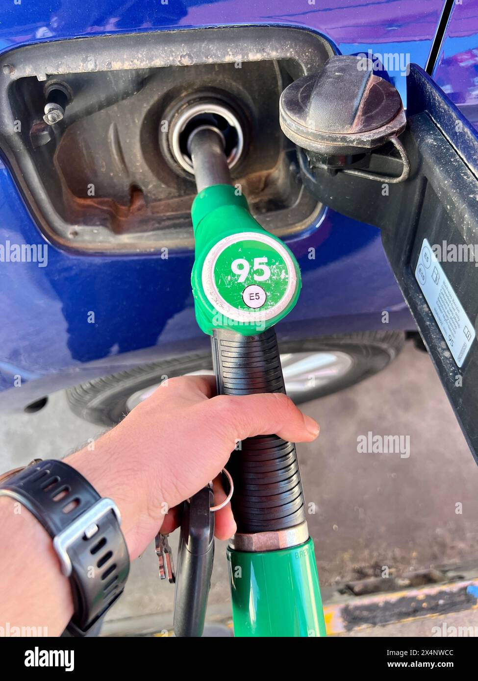 Mano maschile che riempie il serbatoio del gas dell'auto. Primo piano di MAN che fornisce benzina al veicolo. Concetto di aumento della benzina Foto Stock