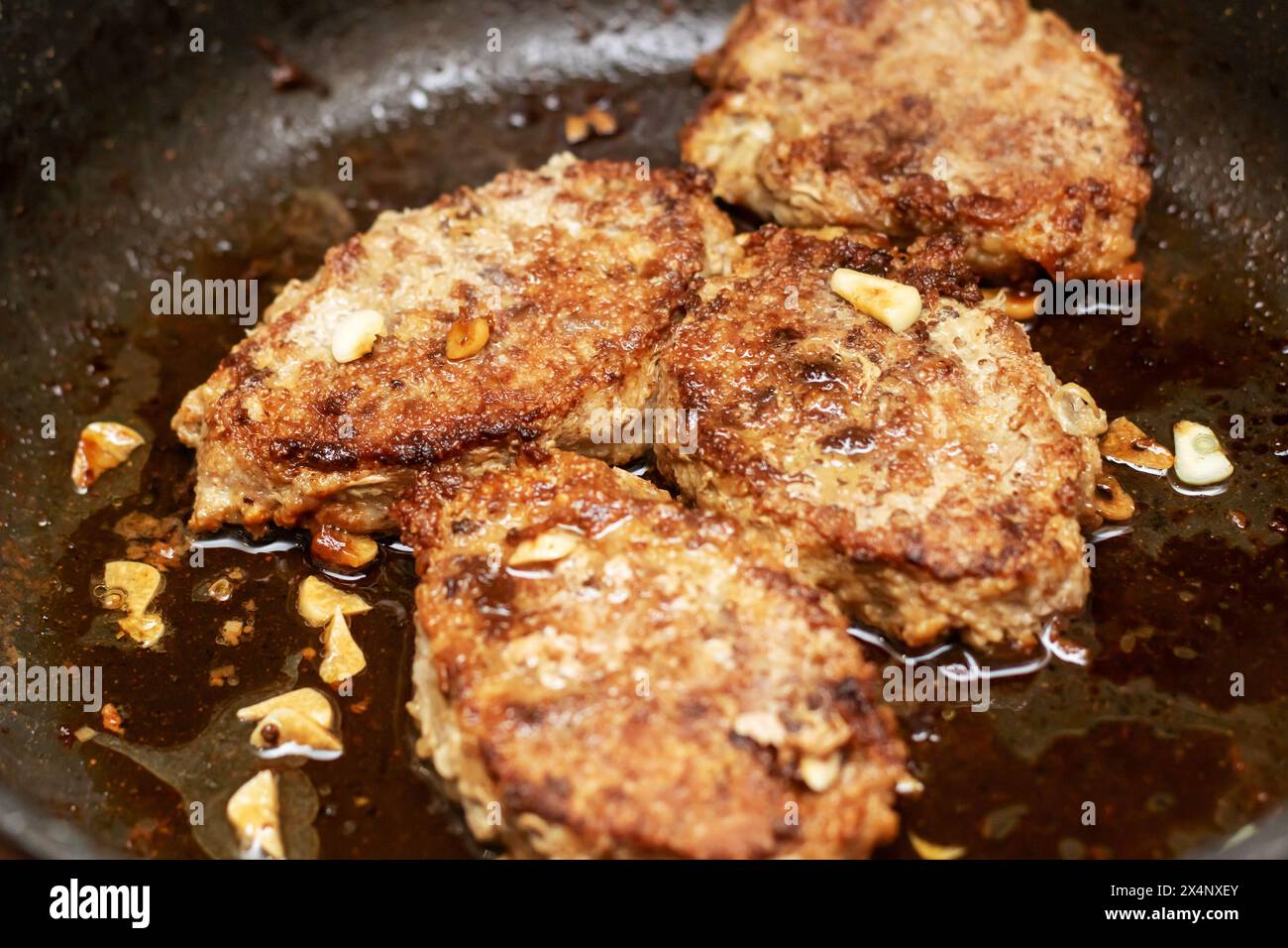 Un taglio di carne sta friggendo in una padella, essendo cucinato alla perfezione. Questo piatto è un classico esempio di frittura profonda in cucina, creando un delizioso Foto Stock