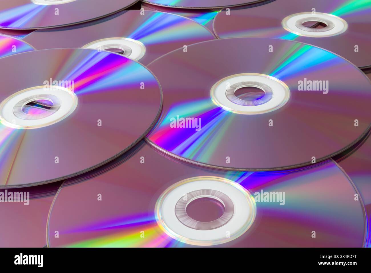 Riflessi arcobaleno su una collezione di compact disc. Una vivace pila di cd con riflessi iridescenti che creano uno spettro di colori. Foto Stock