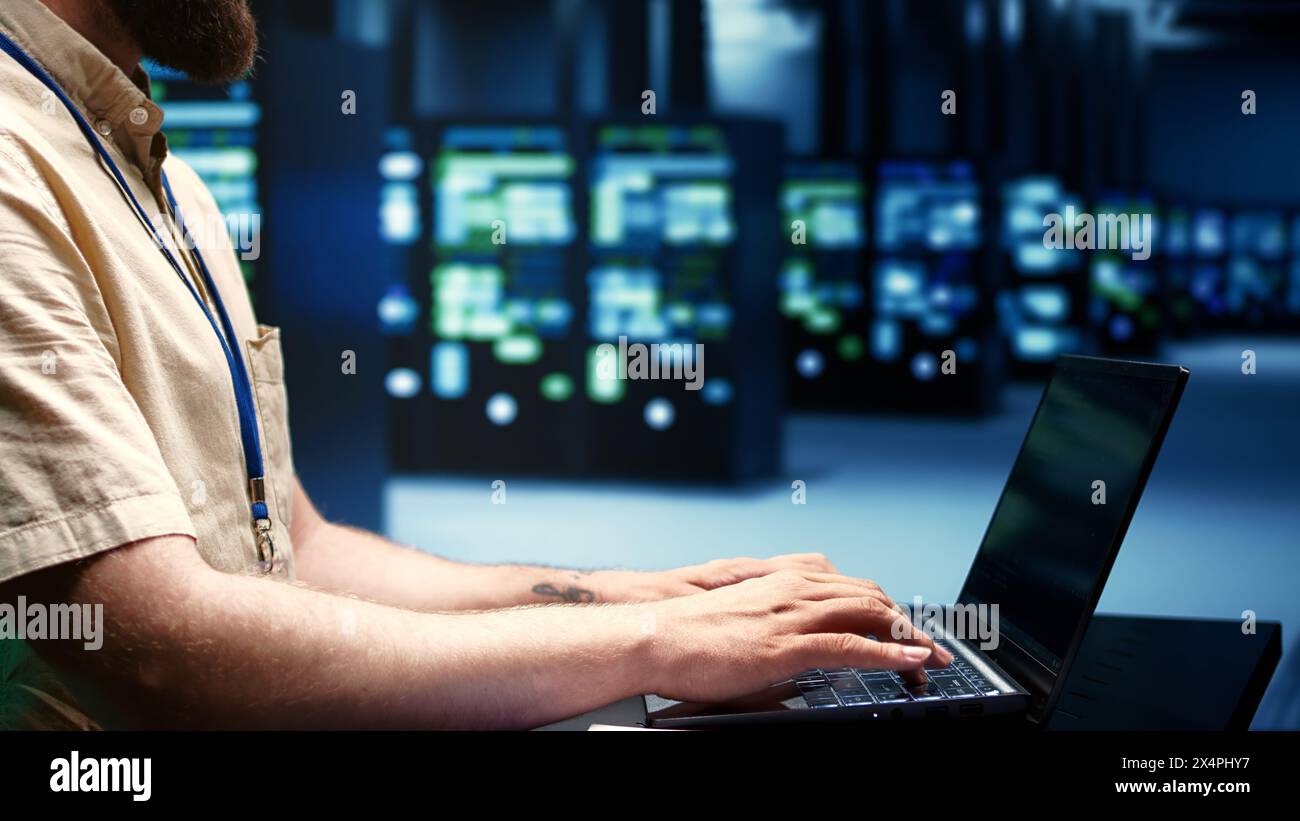 Supervisore che esegue test diagnostici dei server blade e utility di controllo dei bug per determinare e riparare i problemi software. Tecnico che utilizza un laptop per esaminare i sistemi critici, verificare la presenza di difetti, primo piano Foto Stock