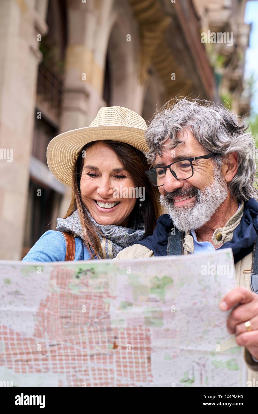 Coppia matura negli anni sessanta sorridente guardando la mappa in Europa città strada. Concetto di viaggio. Foto Stock