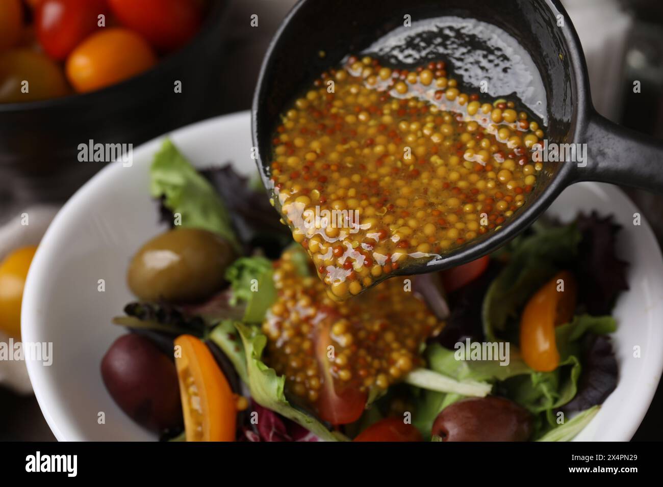 Versare una gustosa salsa a base di aceto (Vinaigrette) nel recipiente con l'insalata e primo piano Foto Stock