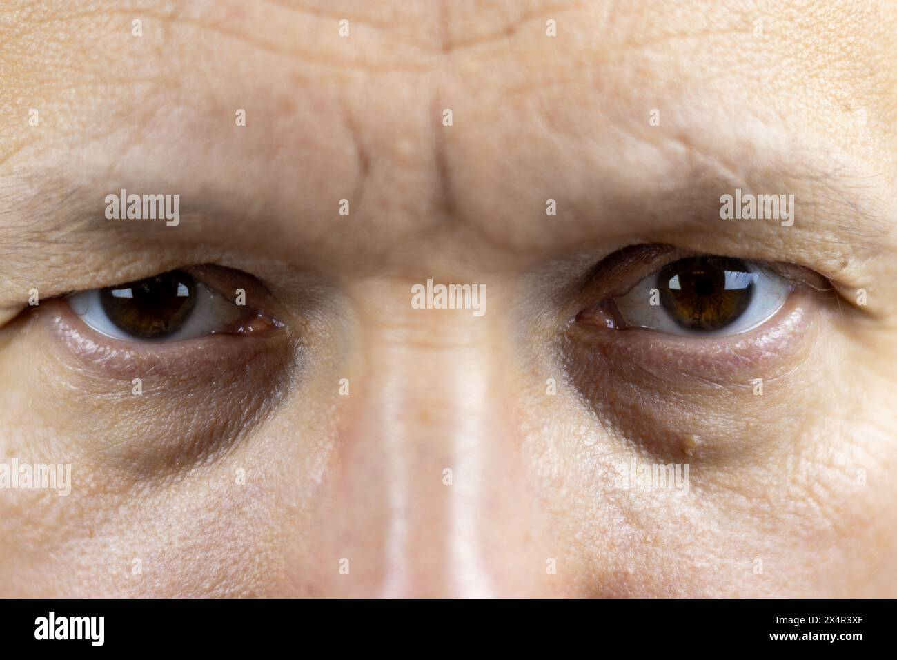 Questa immagine cattura gli occhi marroni e profondi di un uomo di 45 anni. Le rughe e le linee sottili intorno ai suoi occhi raccontano una storia delle esperienze di vita e.. Foto Stock