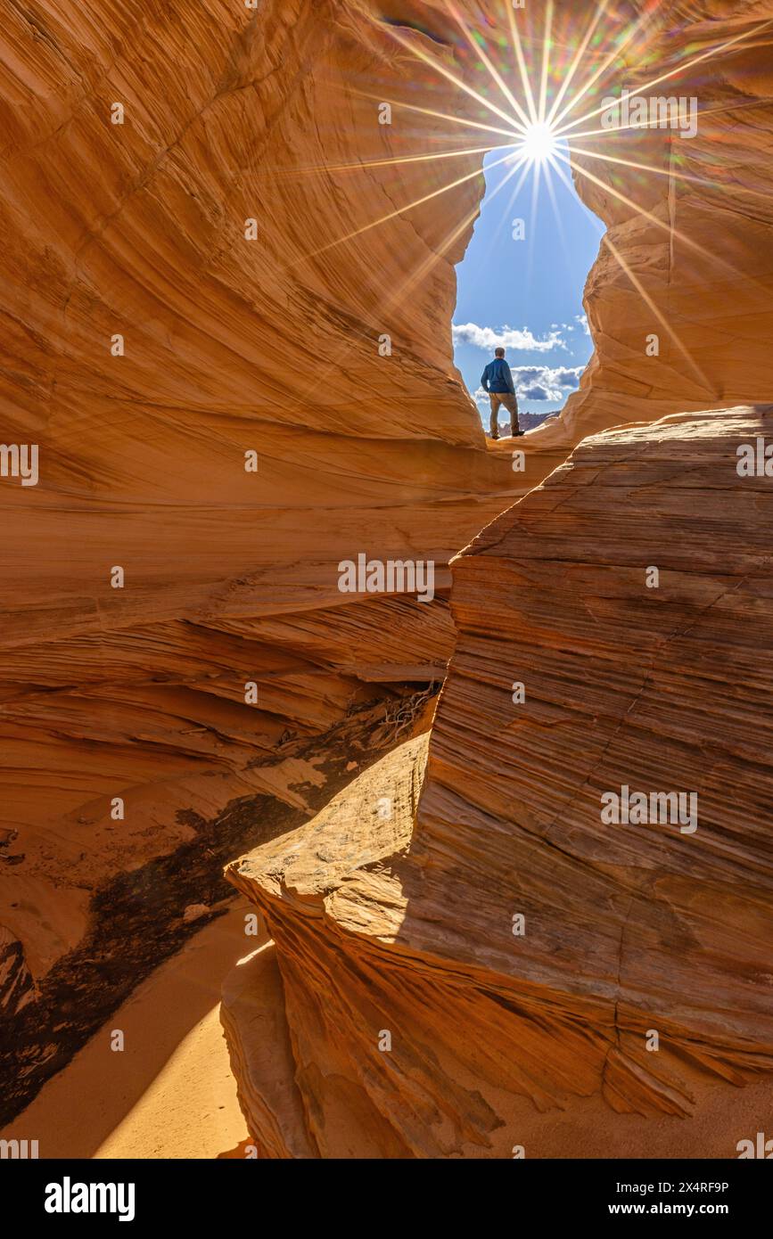 Escursionista in piedi nell'arco Melody con il sole al Marble Canyon Near the Wave, Coyote Buttes North, Vermilion Cliffs National Monument, Arizona, Stati Uniti Foto Stock