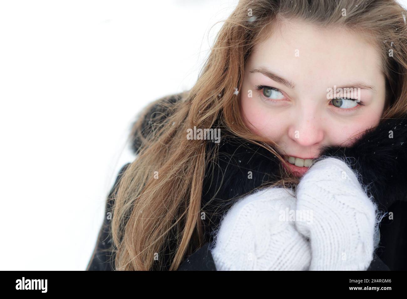 giovane donna sorridente in inverno che si riscalda con guanti e cappotto all'aperto Foto Stock