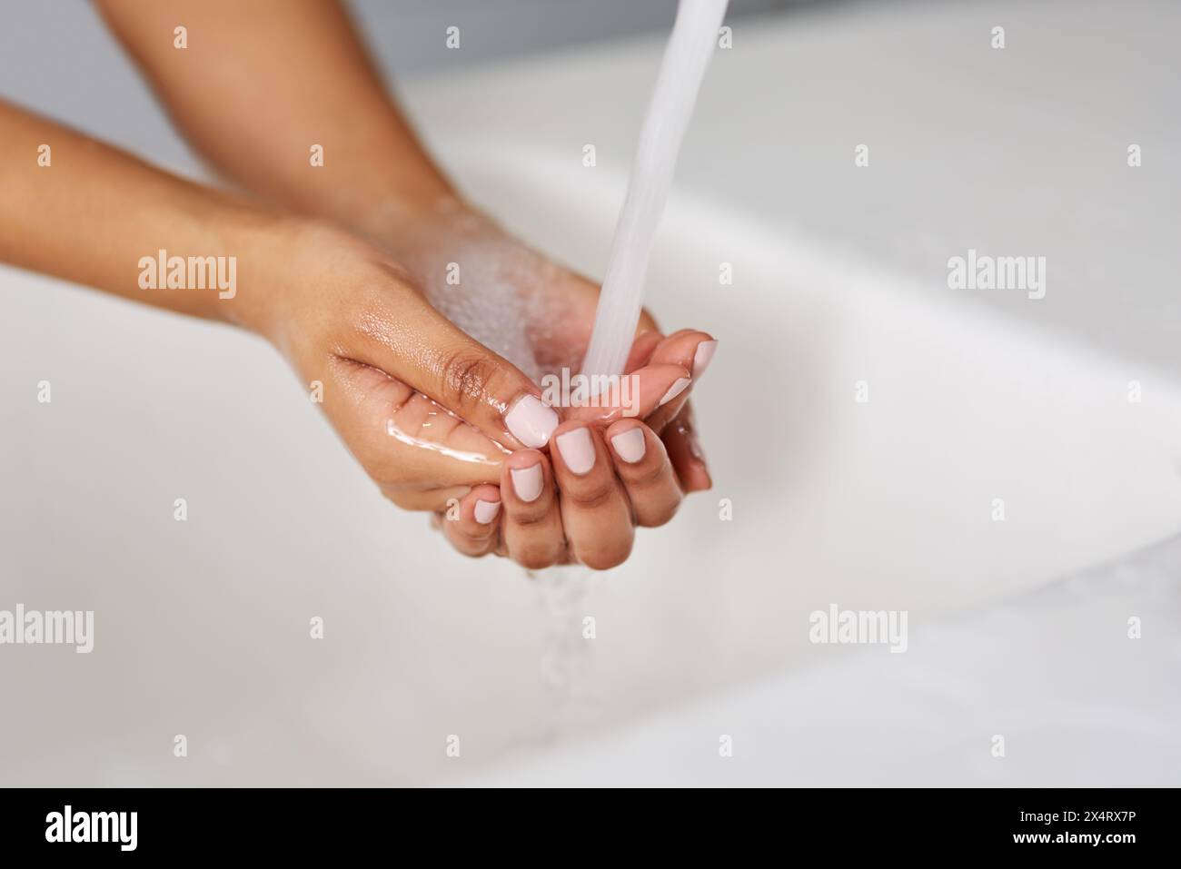 Mani, acqua e rubinetto per la pulizia, lavandino e bagno in primo piano, lavaggio e casa. Persona, benessere e spruzzo per la cura della pelle sana, disinfezione e. Foto Stock