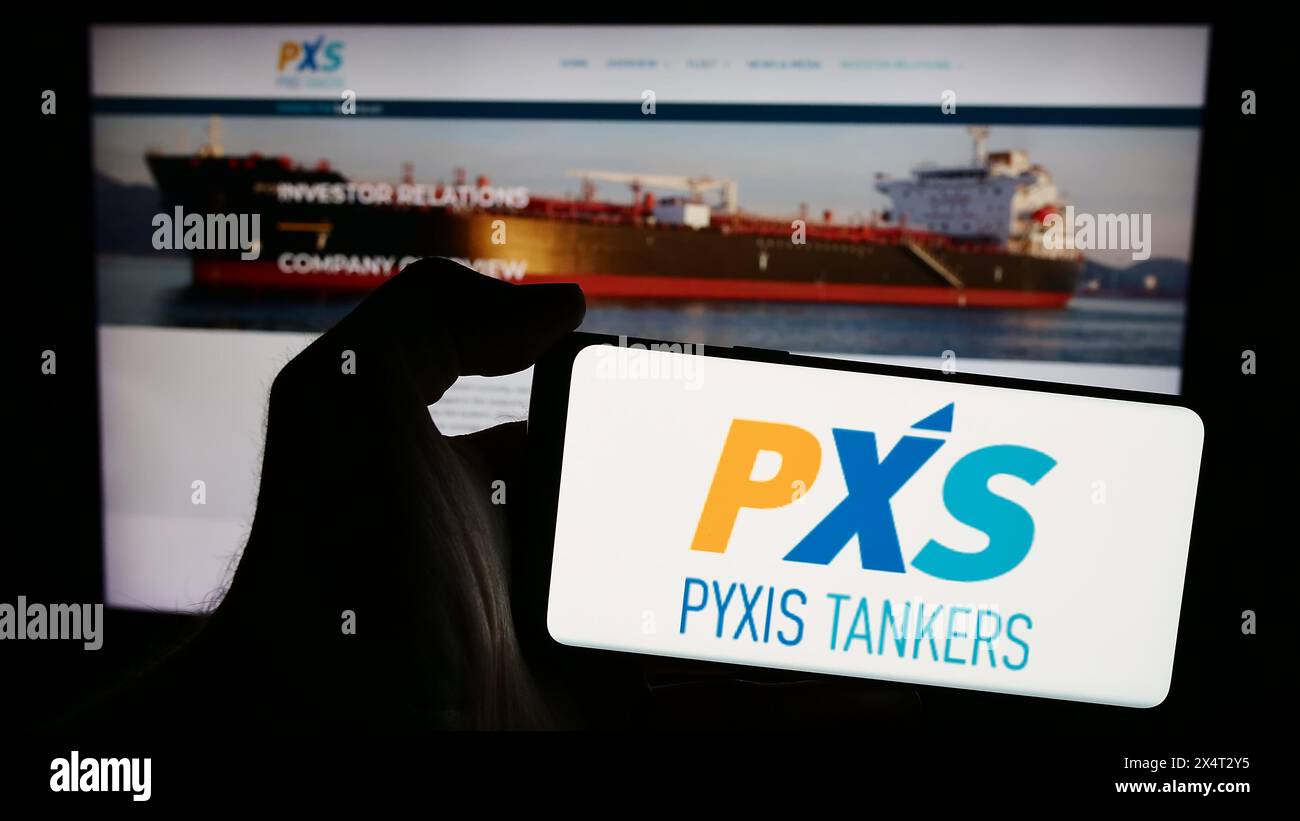 Persona che possiede un telefono cellulare con il logo della società di spedizioni greca Pyxis Tankers Inc. (PXS) davanti alla pagina Web aziendale. Mettere a fuoco il display del telefono. Foto Stock