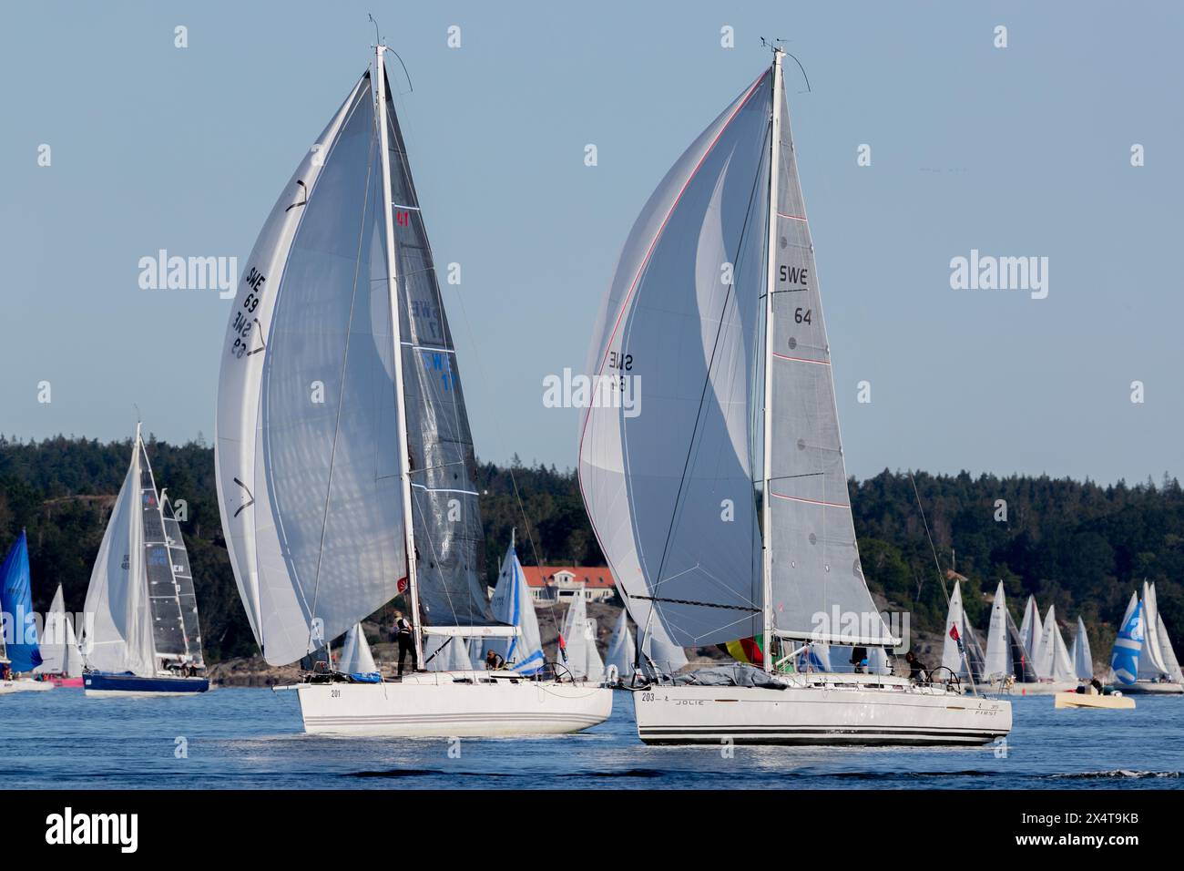 Stenungsund, Svezia - 21 agosto 2021: Due grandi barche a vela in mare in una gara a vela. Barche più piccole sullo sfondo. Equipaggio visibile sulle barche. Foto Stock