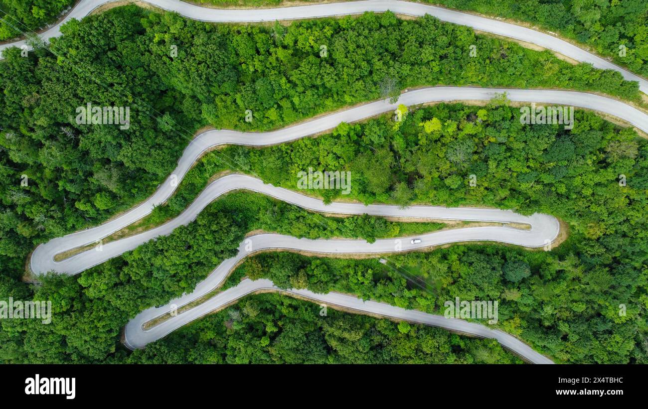 strada di montagna immersa nel verde di una natura incontaminata. Foto in zenithal, dall'alto con un drone di una strada tortuosa che si snoda e gira. natura Foto Stock