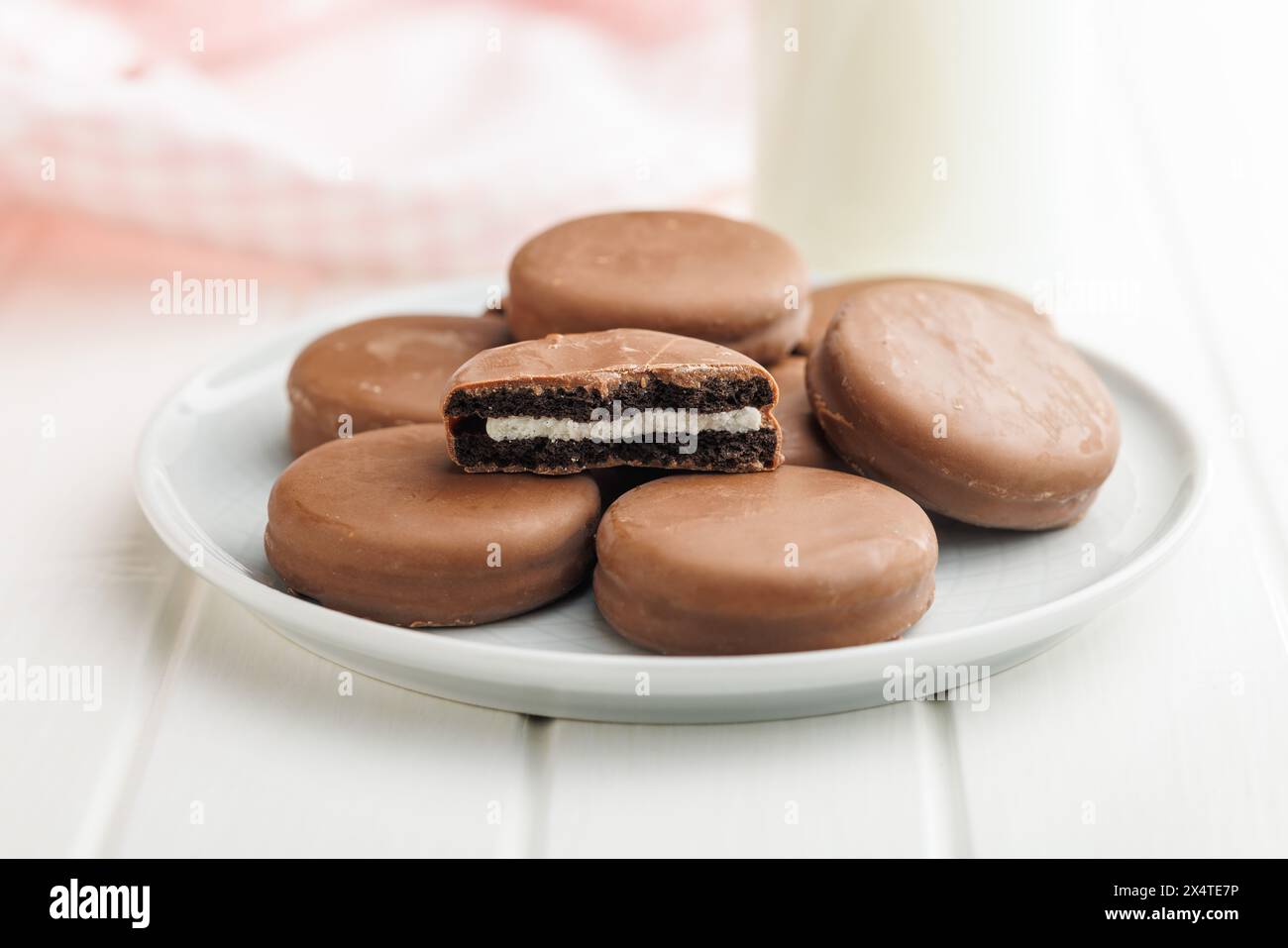 Piatto di biscotti ricoperti di cioccolato e bicchiere di latte Foto Stock