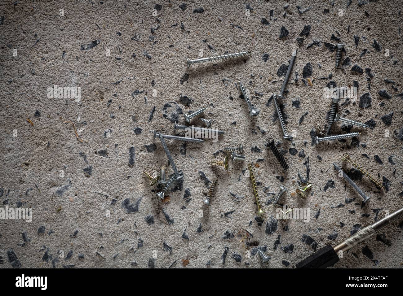 Vite, chiodo su fondo in calcestruzzo. Primo piano di viti e chiodi sul pavimento in cemento con spazio di copia. Foto Stock