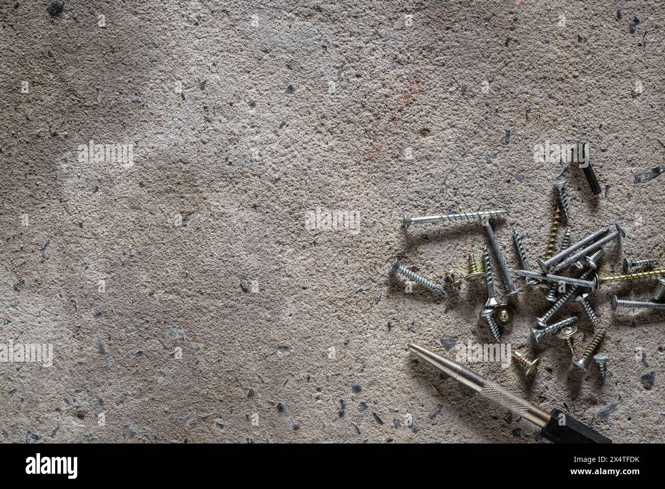 Vite, chiodo su fondo in calcestruzzo. Primo piano di viti e chiodi sul pavimento in cemento con spazio di copia. Foto Stock