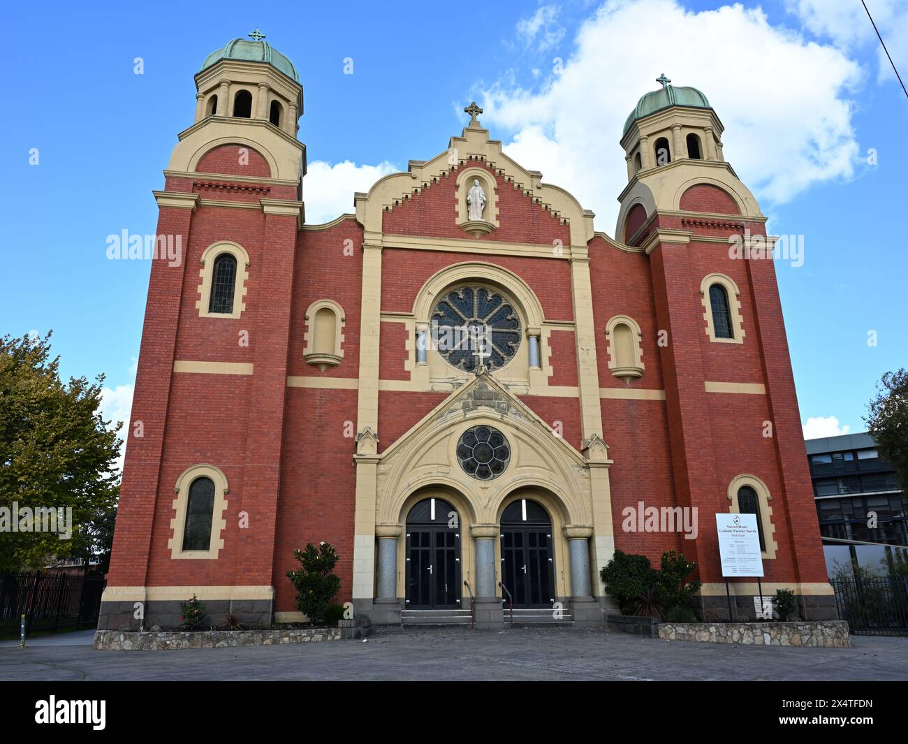 Ingresso frontale dell'imponente chiesa parrocchiale cattolica in mattoni rossi, in Warrigal Rd, durante il giorno Foto Stock