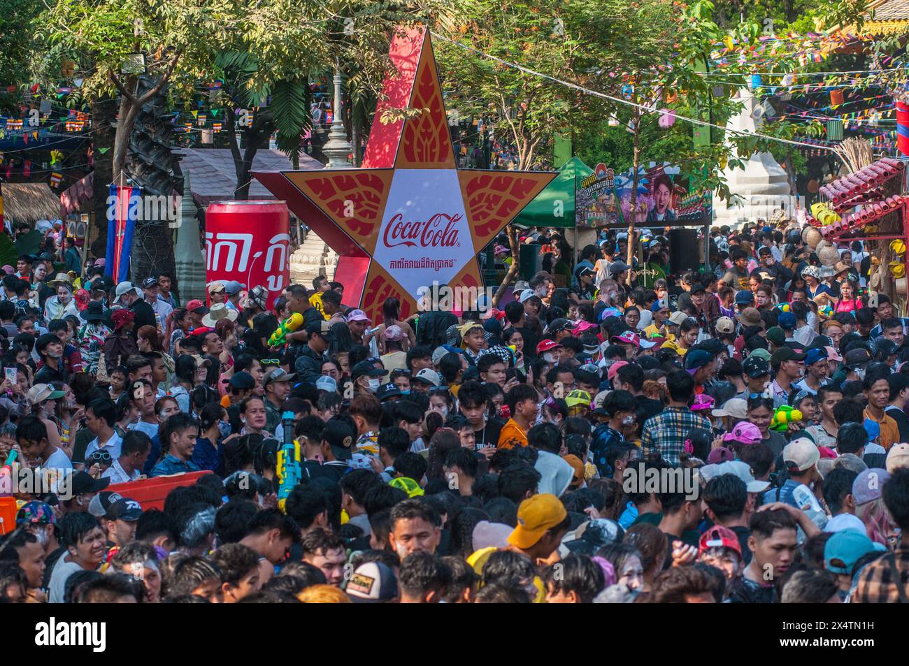 Una folla densamente affollata vicino a una pubblicità bilingue della Coca-Cola durante il festival cambogiano del capodanno. Wat Phnom, Phnom Penh, Cambogia. © Kraig Lieb Foto Stock