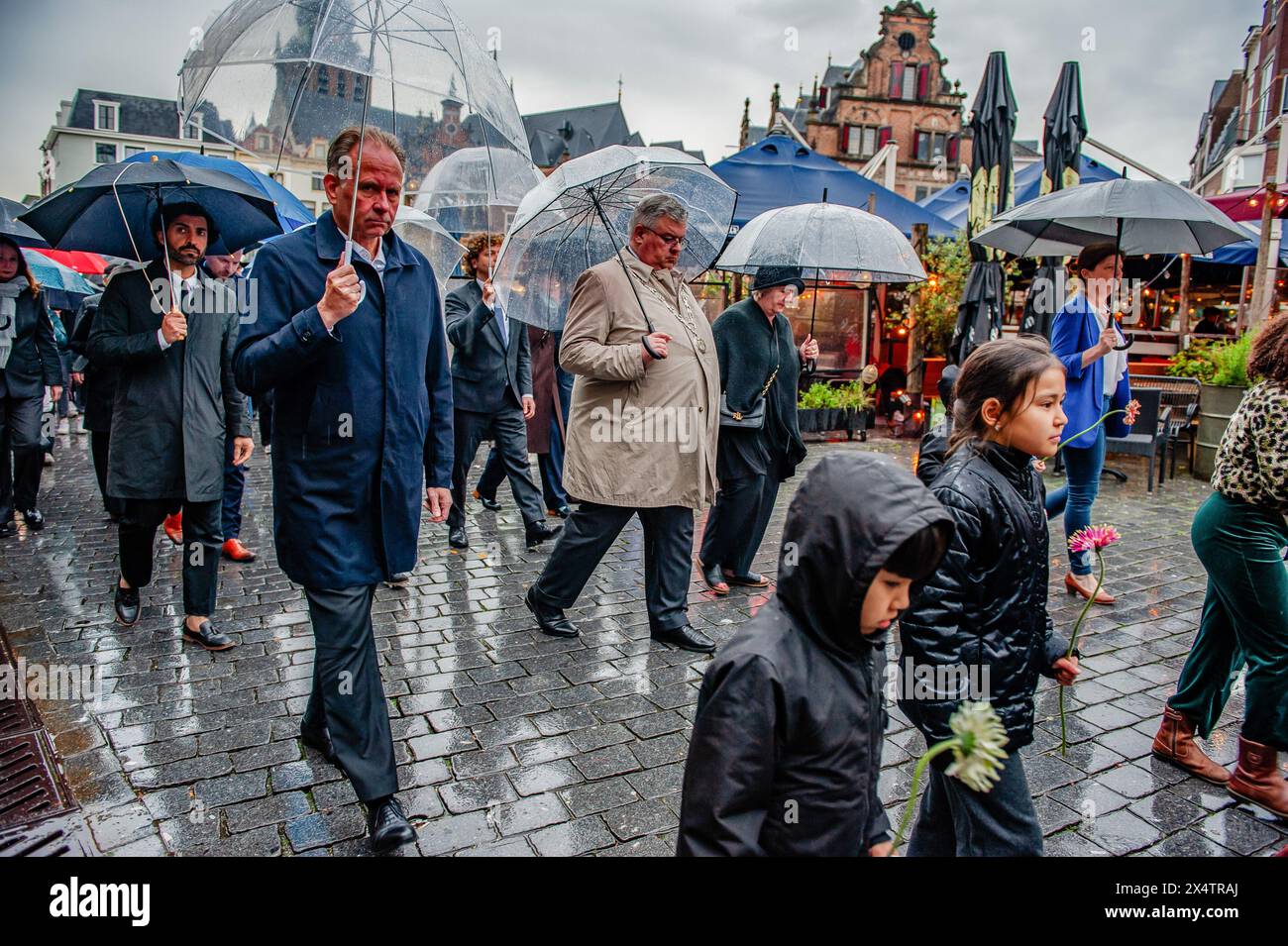 Nijmegen, Paesi Bassi. 4 maggio 2024. Il sindaco di Nijmegen Hubert Bruls (centro) è visto camminare dietro i bambini portando fiori. In questo giorno, l'intero paese commemora civili e soldati durante la seconda guerra mondiale e altri conflitti. A Nimega, una processione silenziosa ha preso le strade fino al "Keizer Traianusplein", dove si ergono due monumenti in ricordo delle vittime della seconda guerra mondiale. La cerimonia ufficiale è iniziata con due minuti di silenzio, e sono state posate delle corone. Credito: SOPA Images Limited/Alamy Live News Foto Stock