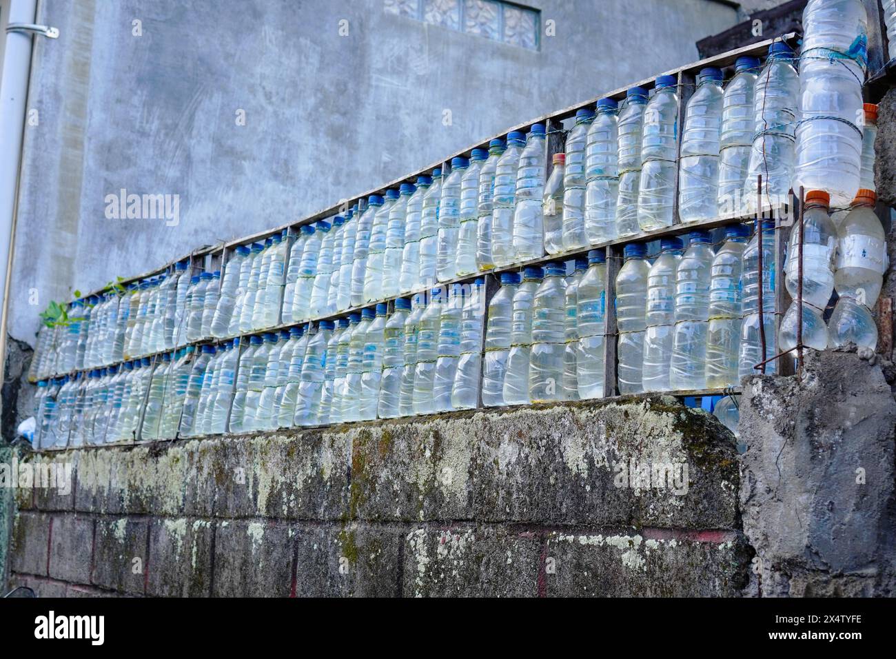 Bottiglia d'acqua blu riciclata usata per far scoppiare un muro Foto Stock