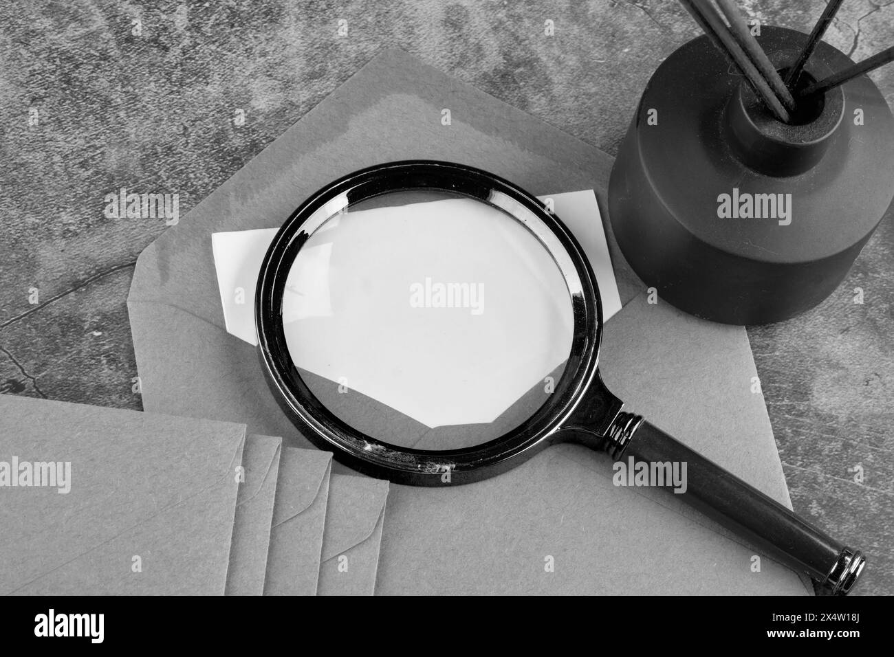 Il concetto di ricerca di documenti segreti. Una lente di ingrandimento su una nota da una busta con un punto in cui copiarla. Immagine in bianco e nero Foto Stock