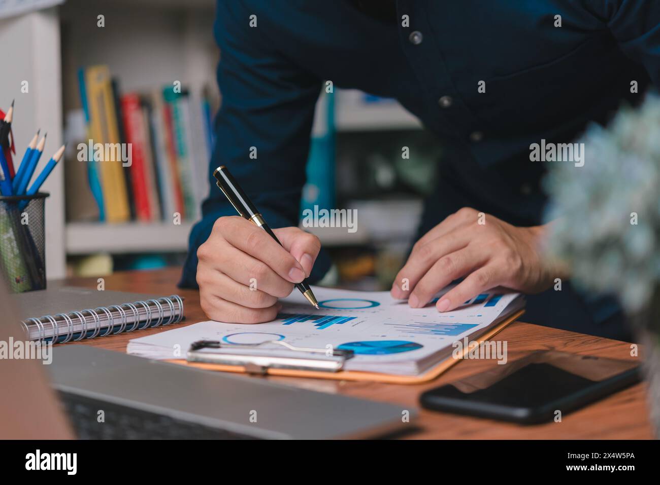 Uno Strategist aziendale mette a punto informazioni su grafici cartacei con analisi, promuovendo decisioni basate sui dati. Foto Stock