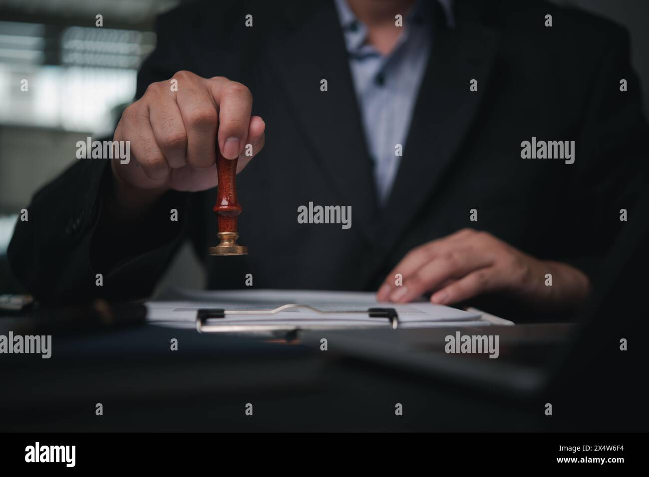 la mano sta premendo sigillo su un documento, che significa riservatezza e timbratura approvazione di attività finanziarie bancarie o investimenti di un accordo. Foto Stock