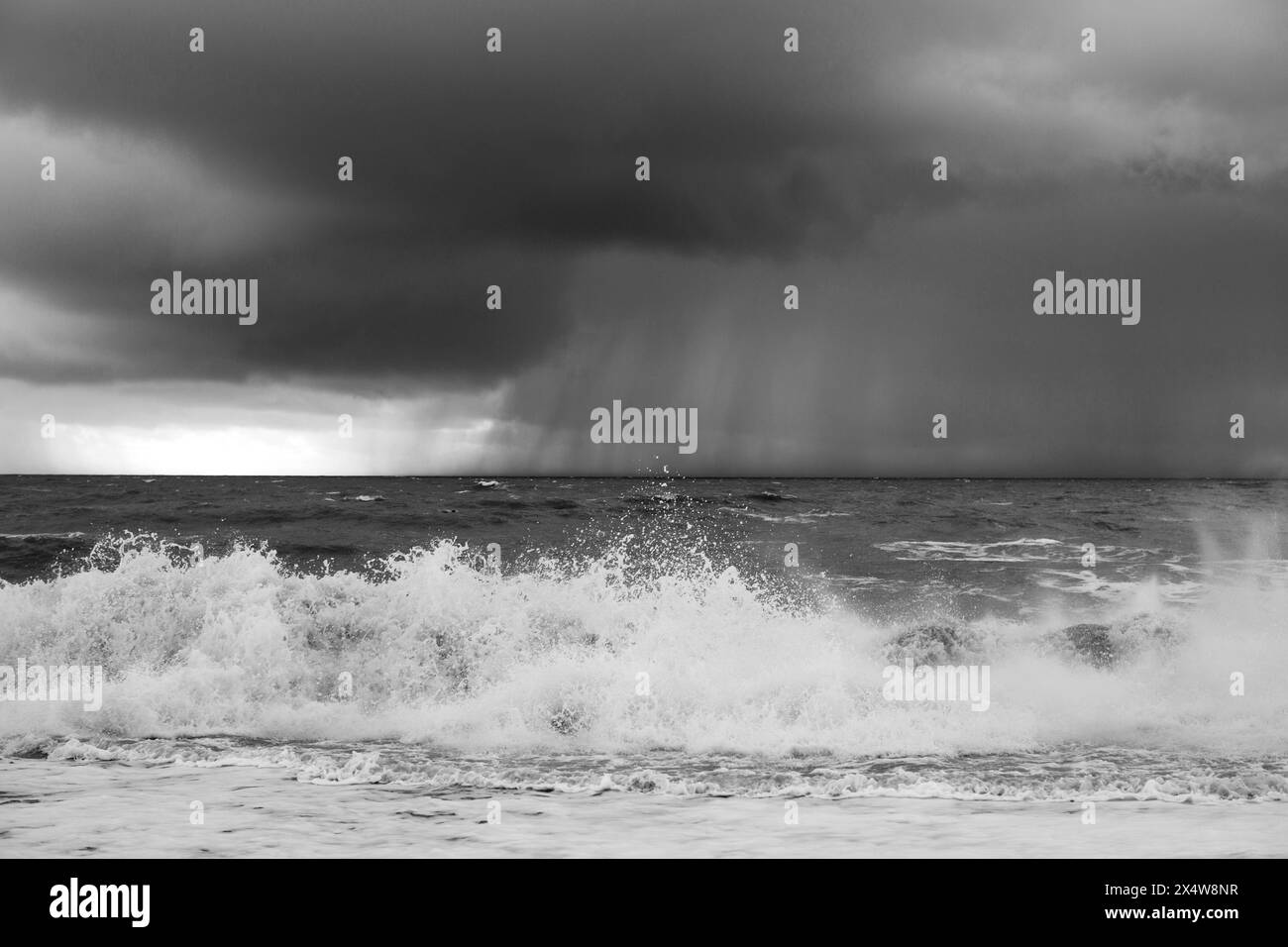 Tempesta in mare a Hastings, Inghilterra. Mare spumeggiante in primo piano con nuvole di pioggia in mare. Foto Stock