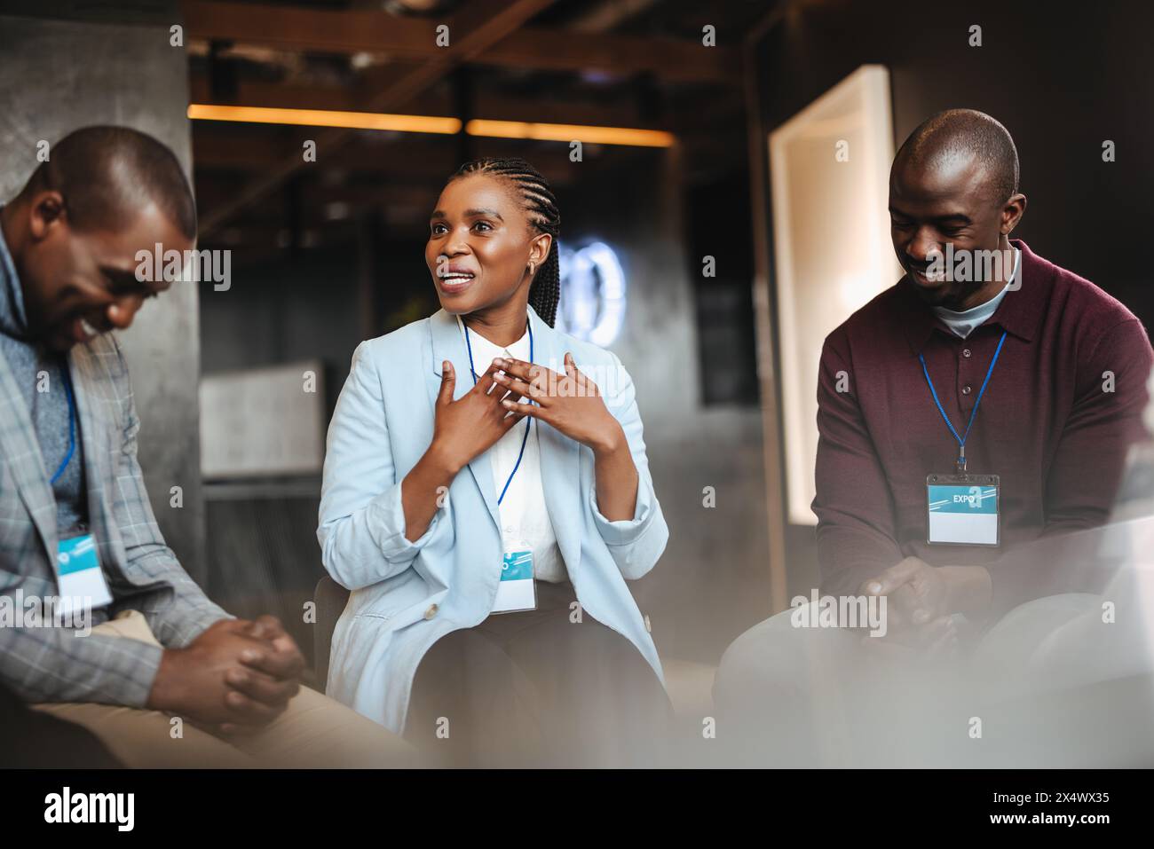 Professionista donna che discute argomenti di business con i colleghi maschi in una conferenza aziendale, evidenziando concetti e networking. Foto Stock