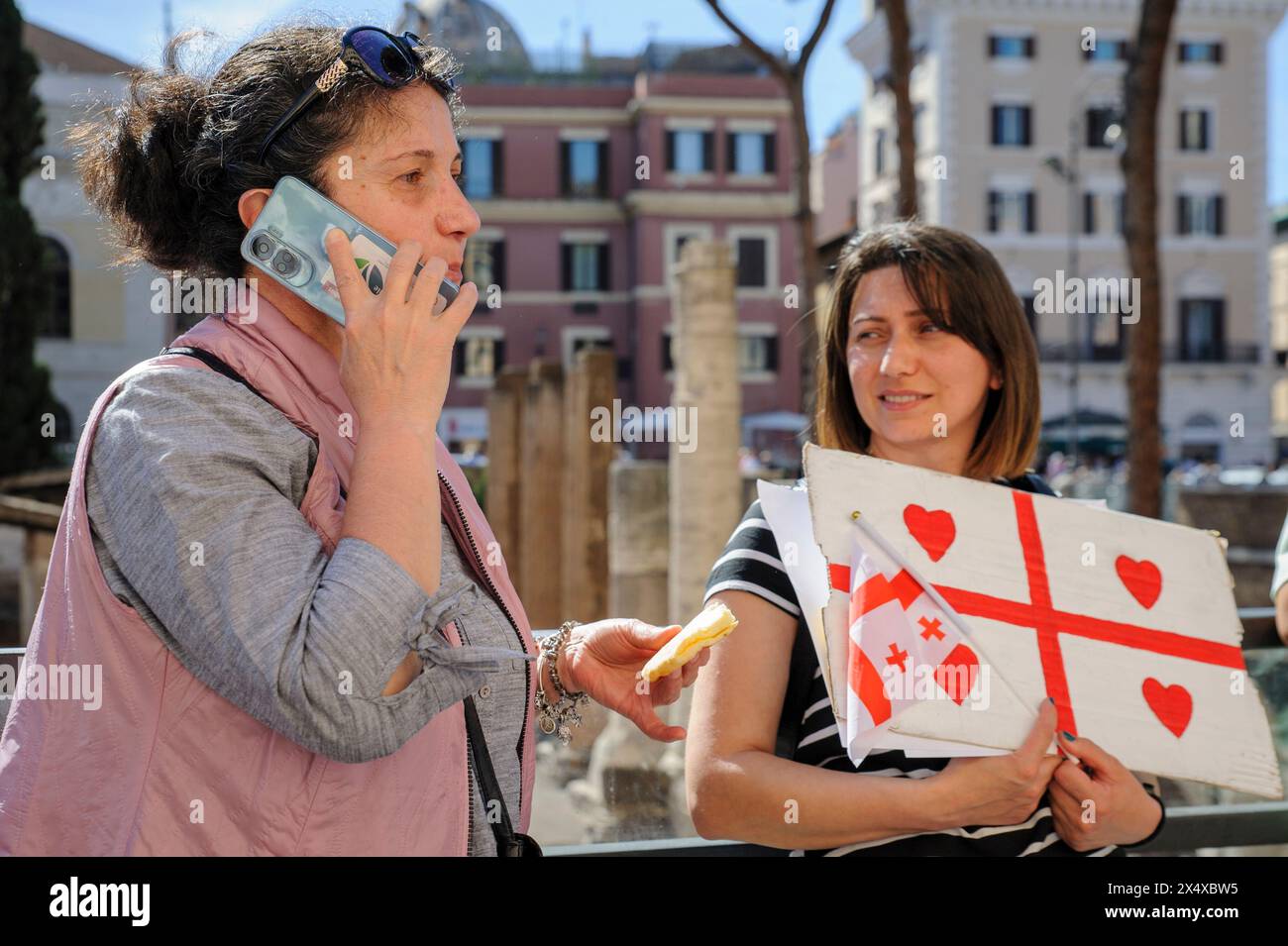 Roma, Italia. 5 maggio 2024, Roma, Italia: Una donna riceve una chiamata dal suo "proprietario" italiano mentre mangia la tradizionale pizza al formaggio (è una badante e non ha avuto il giorno libero per la Pasqua ortodossa) durante la protesta pacifica organizzata da "un gruppo di studenti georgiani auto-organizzati" per protestare contro l'approvazione della cosiddetta "legge russa”, da parte del governo georgiano, a Roma. Crediti: ZUMA Press, Inc./Alamy Live News Foto Stock