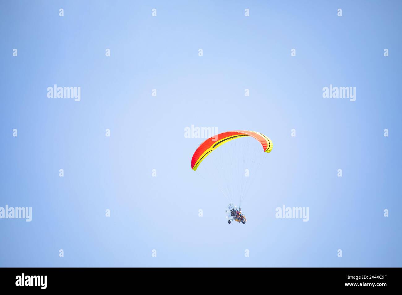 Volo tandem motorizzato con paratrike, parapendio motorizzato a due posti con ruote. persone irriconoscibili in alto nel cielo su un trike motorizzato Foto Stock