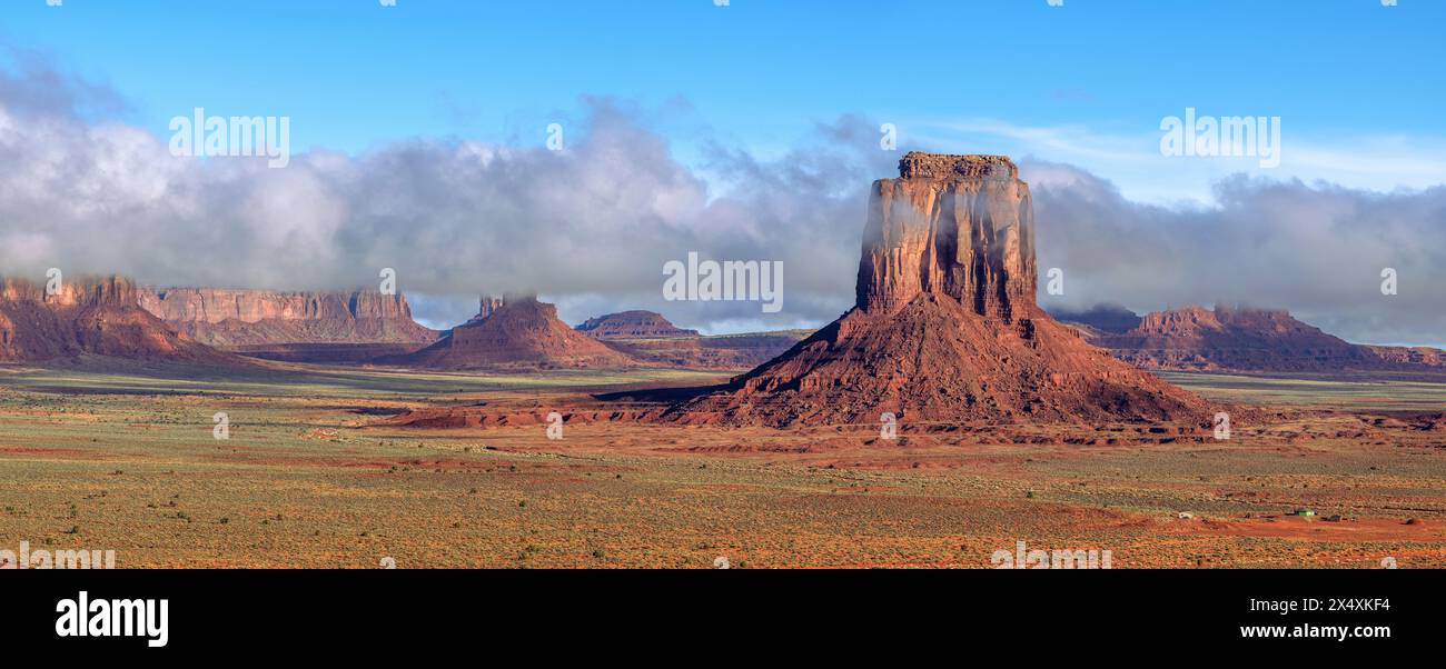 I rainclouds bassi abbracciano una butte nel Navajo Tribal Park della Monument Valley, mentre la pioggia idrata il terreno arido del deserto. Foto Stock