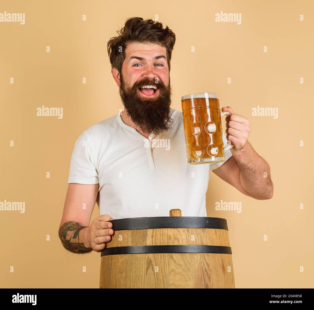 L'ora della birra. Uomo con barba felice che assaggia birra alla spina nel pub o nel bar. Un bell'elegante ragazzo con una tazza di birra al ristorante. Bevande alcoliche. Oktoberfest Foto Stock